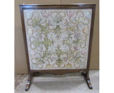 A 19th century handworked panel in the Tudor style depicting flowers set within a walnut frame presented as a firescreen, the