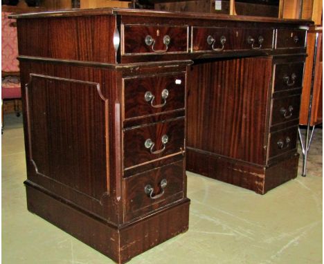 A reproduction Georgian style mahogany veneered kneehole twin pedestal writing desk with inset green leather top over eight f