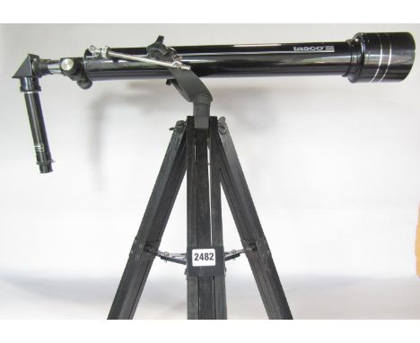 A Tasco Telescope mounted on an adjustable tripod, together with some spare eyepiece parts. 