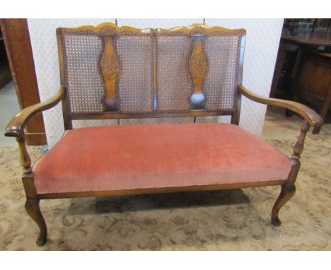 An Edwardian parlour room or bedroom sofa with polished show wood frame, cane panelled back, recently re-upholstered seat on 