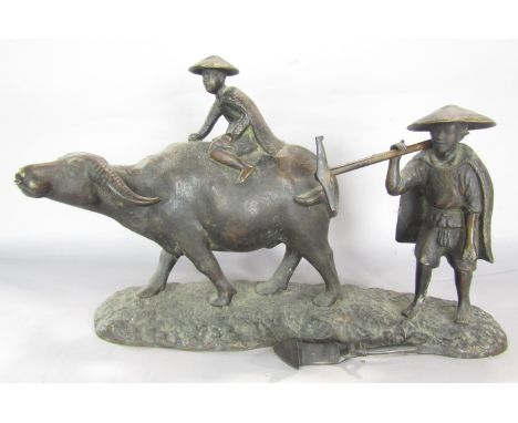 A South East Asian bronze group of a boy riding a water buffalo with his father in attendance, as found, 41cm wide. 