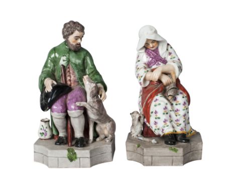 A pair of Continental porcelain figures of a seated bearded man and his wife, possibly Russian, late 19th century, he with a 