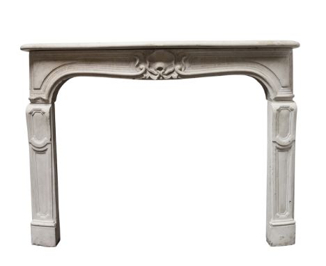 A French Louis XV stone cheminee, circa 1780, with a serpentine shaped  shelf,  over a panel frieze carved with a central she