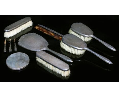 A SILVER MOUNTED DRESSING TABLE SET consisting of a mirror and two pairs of brushes, together with a white metal compact and 