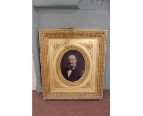 A late 19th Century French portrait photo of a gentleman in an oval gilt mount within a heavily moulded gilt rectangular fram