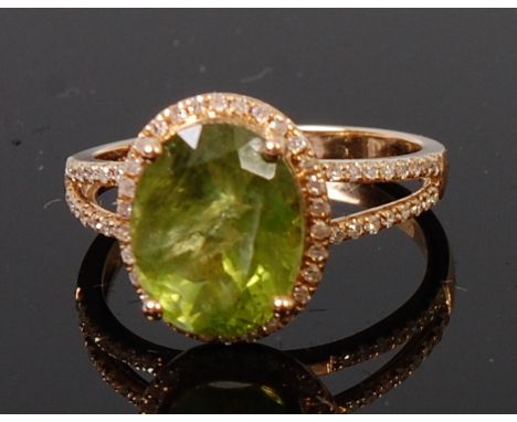 A contemporary 14ct yellow gold, green peridot and diamond set dress ring, the oval cut peridot weighing approx 4.4ct, in a s