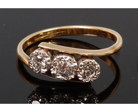 A vintage 18ct gold and diamond three stone ring, the illusion set old brilliants in a line setting, the largest weighing app