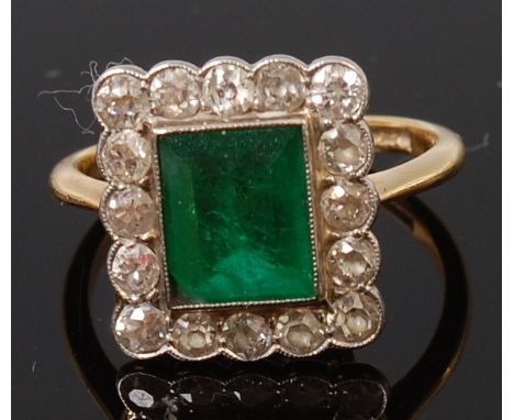 An Art Deco 18ct gold, emerald and diamond ring, the baguette cut emerald measuring approx 7.5 x 6mm, in a surround of sixtee