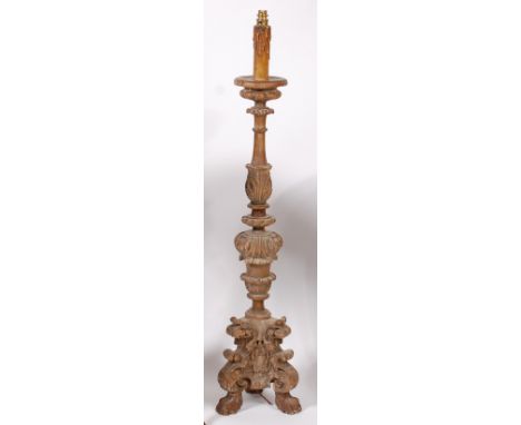 An 18th century Baroque carved and limed softwood alter stick, of good size, having knopped column to a triform base on paw f