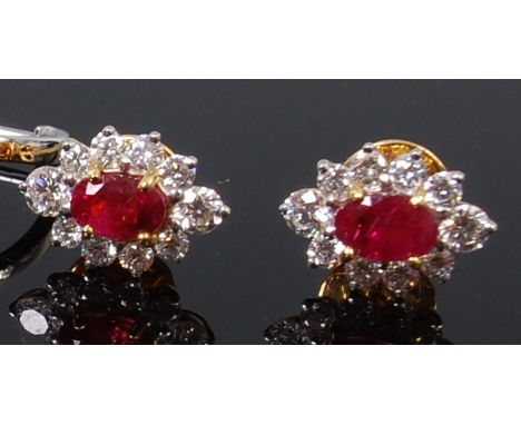 A pair of yellow metal, ruby and diamond set ear studs, arranged as a centre four claw set oval cut ruby weighing approx 0.3c