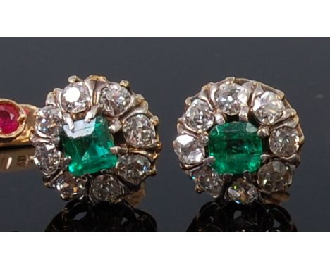 A pair of yellow metal, emerald and diamond set ear studs, as a flower head setting, having a centre old square cut emerald w
