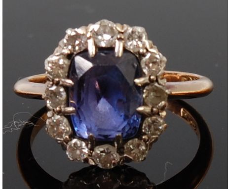 An 18ct gold, sapphire and diamond cluster ring, the fancy trap cut blue sapphire weighing approx 3.6ct, in a surround of twe