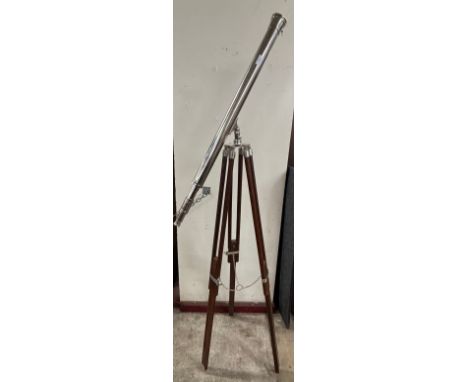 A chrome telescope on an adjustable teak tripod stand 