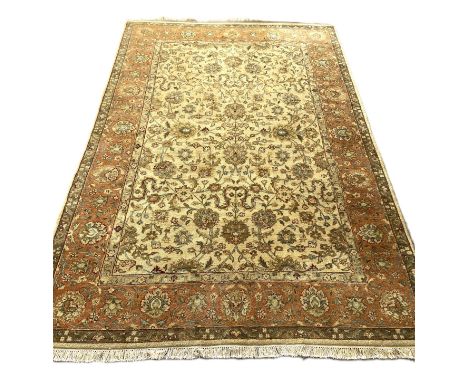A modern Persian style wool mix carpet, with floral arabesques on a caramel ground, within guard stripes; 270cm x 175cm
