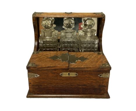 A Victorian oak cased tantalus, fitted with three spirit decanters, a humidor compartment and sprung loaded drawer (concealed