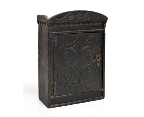 Late 17th or early 18th century carved oak spice cupboard, the arched cresting with carved scrollwork and central roundel, ov