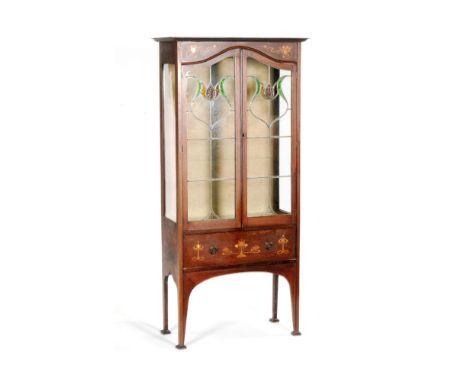 An Edwardian Art Nouveau inlaid mahogany display cabinet enclosed by a pair of coloured leaded light glazed doors above a bas