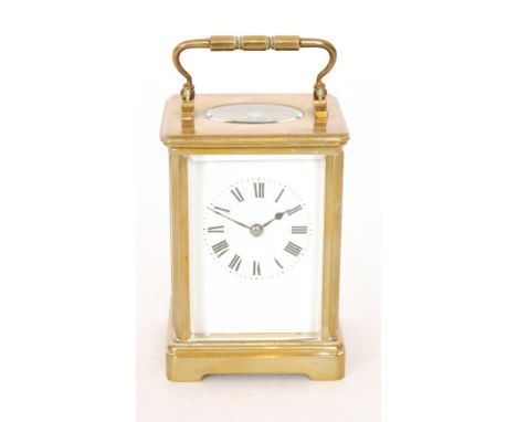 An early 20th Century brass carriage clock with Roman numerals to a white enamelled dial, all below carrying handle, height 1
