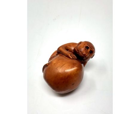 A carved Chinese hardwood netsuke - Monkey on fruit
