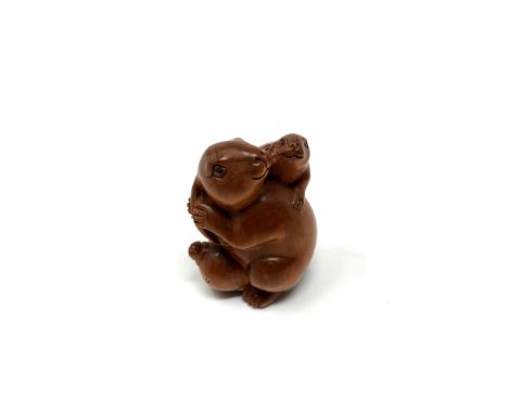 A carved Chinese hardwood netsuke - Rabbit seated on fruit