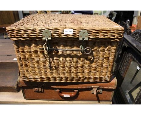 A vintage tan suitcase together with woven wicker hamper