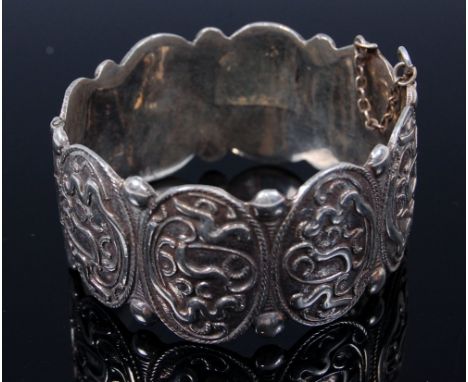 A Persian white metal and embossed hinge bangle
