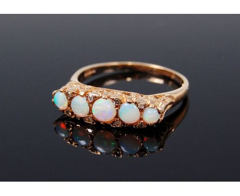 An Edwardian style 9ct gold opal set ring, each graduated cabochon opal dispersed with twin diamond points, 3.2g, size R/S