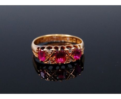 An 18ct gold ruby three stone ring, each ruby dispersed with twin diamond points, 3g, size M