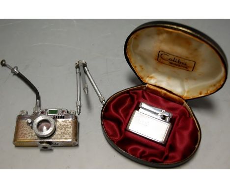 A Lumix table cigarette lighter in the form of a camera on stand, together with a cased chrome Colibri lighter