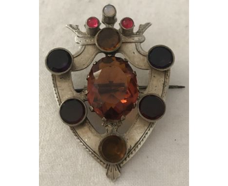 A vintage white metal shield shaped brooch with coronet decoration set with semi precious stones. Stones to include garnets, 
