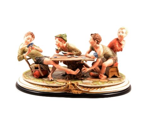 Large Capodimonte group, The Card Cheats, signed Merli, on a mahogany effect oval plinth, length 58cm.Condition report:The fo