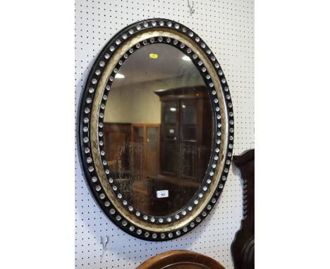 A 19th century oval wall mirror, in black and silvered frame decorated glass beads, 28" x 22" (silvering degrading)