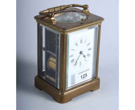 A French early 20th century brass and four glass carriage clock with white enamelled dial and carrying handle, on shaped brac