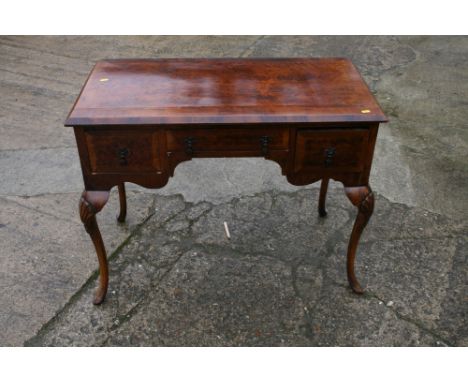 A figured walnut and banded lowboy of Queen Anne design with axe head handles, on cabriole supports, 36" wide