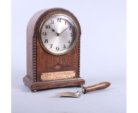 An early 20th century oak cased mantel clock with silvered dial and Masonic inscription and a Masonic trowel paper knife