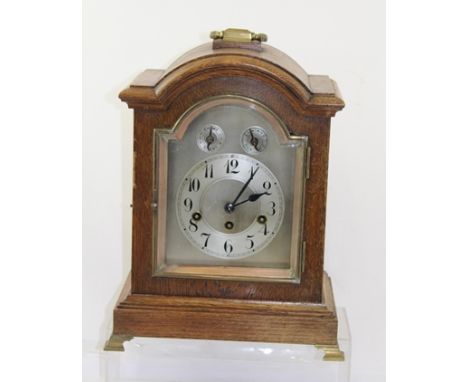 A 1920's OAK CASED JUNGHANS BRACKET CLOCK having arched case with handle, eight day mechanism with gong strike faced by silve