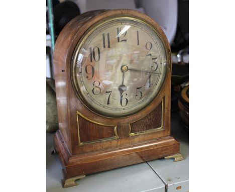 AN EDWARDIAN MAHOGANY CASED MANTEL CLOCK having silvered dial with Arabic numerals, raised on brass ogee bracket feet, 35cm h