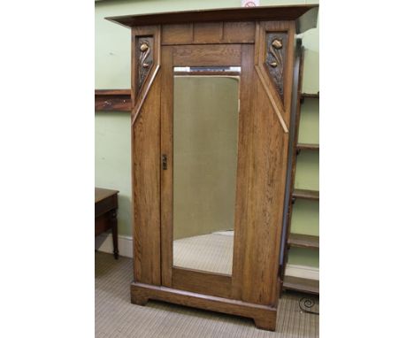 AN ART NOUVEAU DESIGN OAK SINGLE DOOR WARDROBE decorated with beaten copper floral panels, raised on bracket feet, 133cm wide