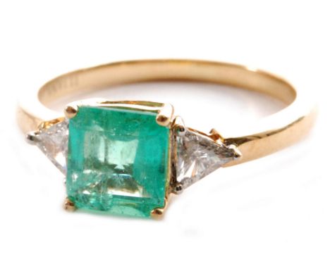 A modern 18ct hallmarked emerald and diamond three stone ring,central square cut emerald flanked by a trillion cut diamond to