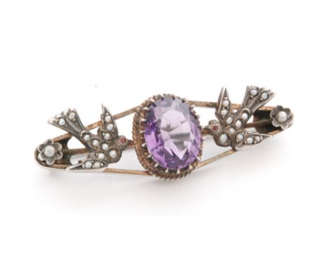 An early 20th Century oval brooch with a central claw set amethyst flanked by two swallows with seed pearl decoration, indist