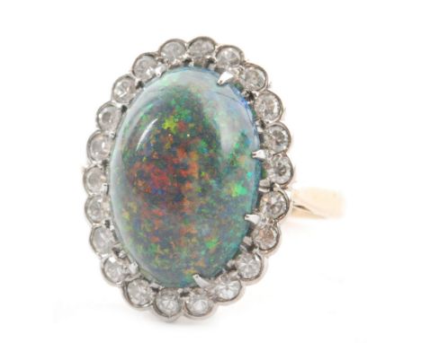 A mid 20th Century 18ct black opal and diamond cluster ring, central cabochon cut domed opal, length 14mm, within twenty two 