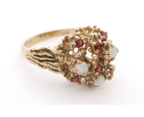 A 9ct hallmarked 1970s abstract ring set with six garnets and three opals to a rough domed head, London 1975, ring size Q