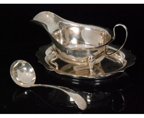 A hallmarked silver matching sauce boat, stand and ladle, all of plain form with scalloped edged borders, Sheffield 1939/40, 
