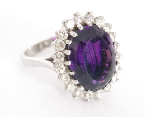 A mid 20th Century 18ct white gold amethyst and diamond cluster ring, central oval amethyst, length 15mm, within a twenty bri