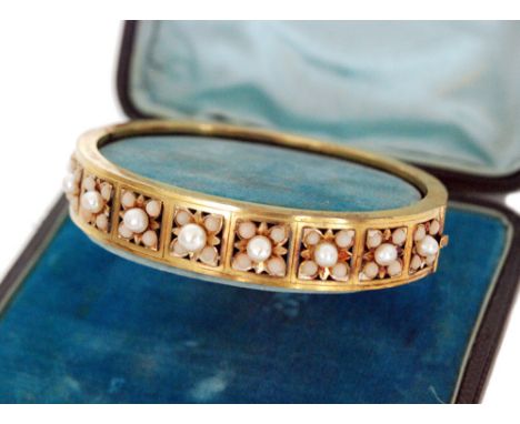 A late 19th Century 15ct seed pearl and coral hinged bangle comprising nine square panels each with central pearl within a fo
