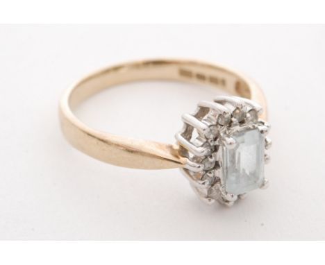 A modern 9ct hallmarked aquamarine and diamond cluster ring, emerald cut aquamarine within a fourteen stone diamond surround,