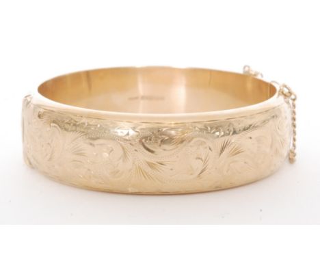 A 9ct hallmarked hinged bangle with part foliate engraved decoration weight 29.5g, Birmingham 1961
