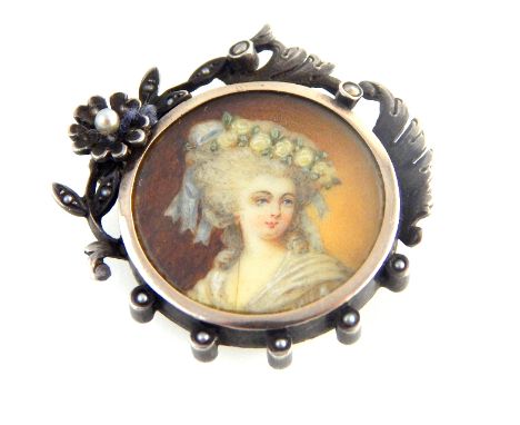 Late Victorian silver portrait brooch depicting head and shoulder bust of an elegant lady in white bonnet, in seed pearl flor