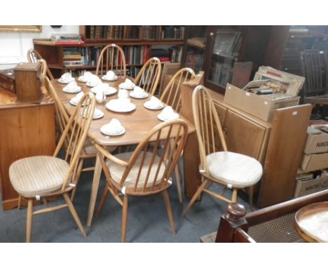 Ercol: A pale elm and beech dining suite comprising extending dining table, ten spindle-back dining chairs, sideboard and wal