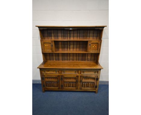 `A REPRODUCTION OAK DRESSER, the top with a central shelf flanked by two single cupboard doors, the base with three drawers a